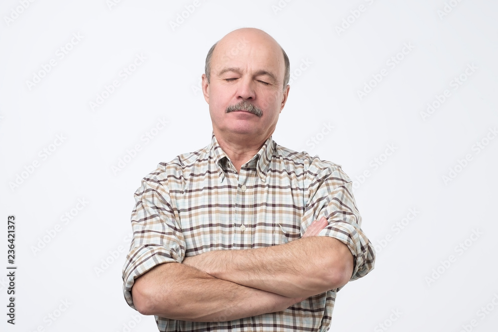 A senior bald man is asleep while standing. He is exhausted at work and need a minute to rest. A senior bald man is asleep while standing. He is exhausted at work and need a minute to rest.