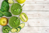 Two green smoothies with ingredients on light wooden table. Top view. With Copy space