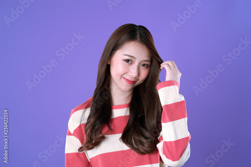 Long hair Korean woman looking and touch her hair, winter t-shirt clothing, purple background