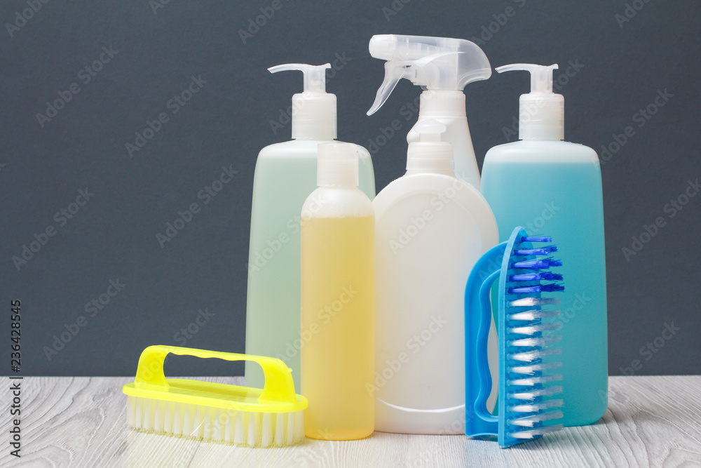 Bottles of detergent and brushes for cleaning on gray background. Bottles of detergent and brushes for cleaning on gray background.