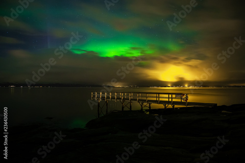 Green Aurora Borealis on night sky.