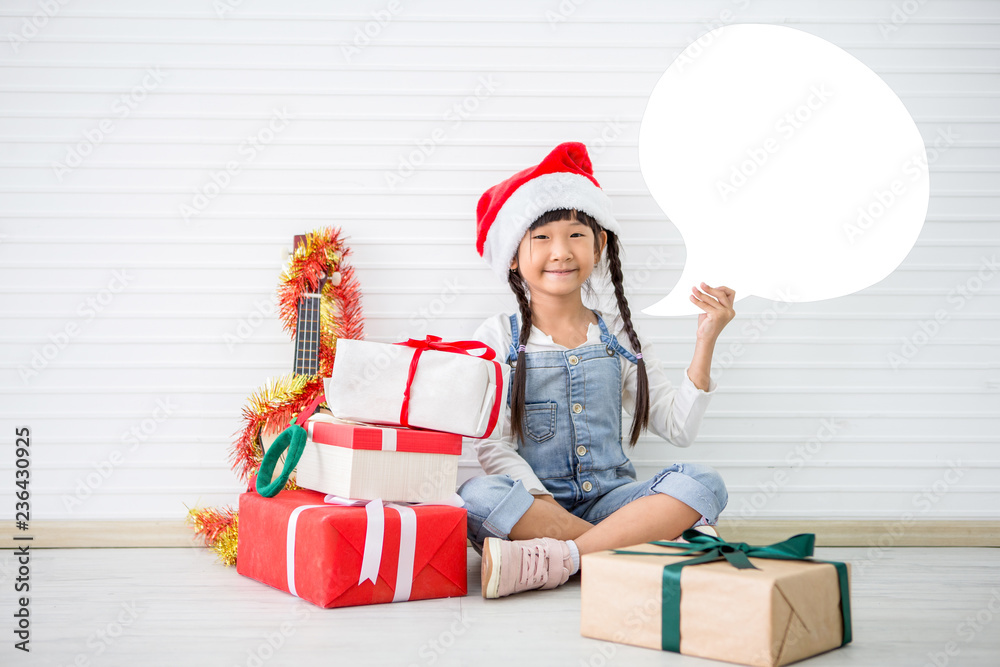 asian girl in Christmas Santa hat show gift box with pile of presents and Ukulele on white background . Chinese childen celebrating happy new year. kid smiling with sketch speech bubble copy space asian girl in Christmas Santa hat show gift box with pile of presents and Ukulele on white background . Chinese childen celebrating happy new year. kid smiling with sketch speech bubble copy space