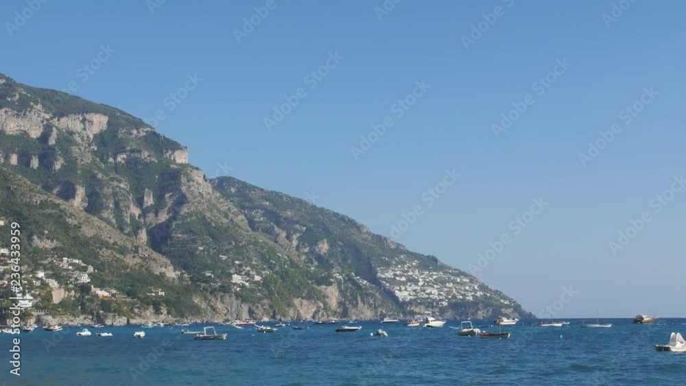 Mountaine rise above blue sea with lots of water crafts on its surface. Positano, Italy Mountaine rise above blue sea with lots of water crafts on its surface. Positano, Italy
