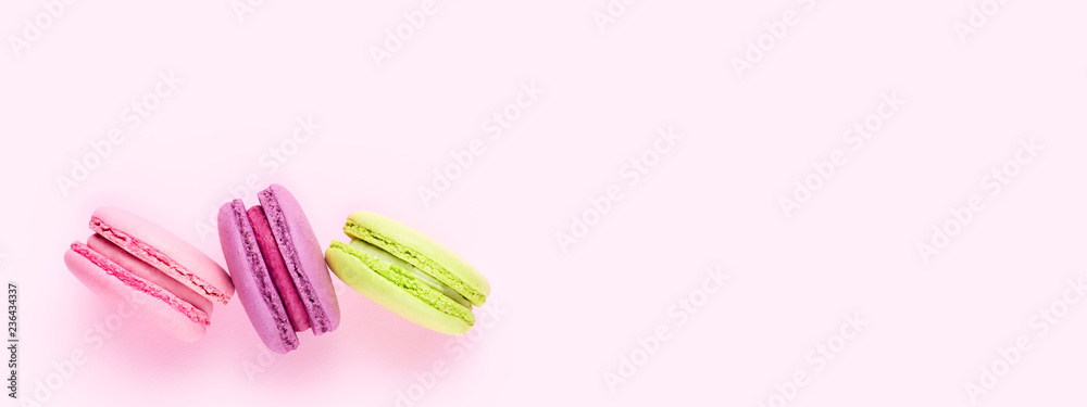 Three colorful macaron cookies on pink background. Top view, minimal design.