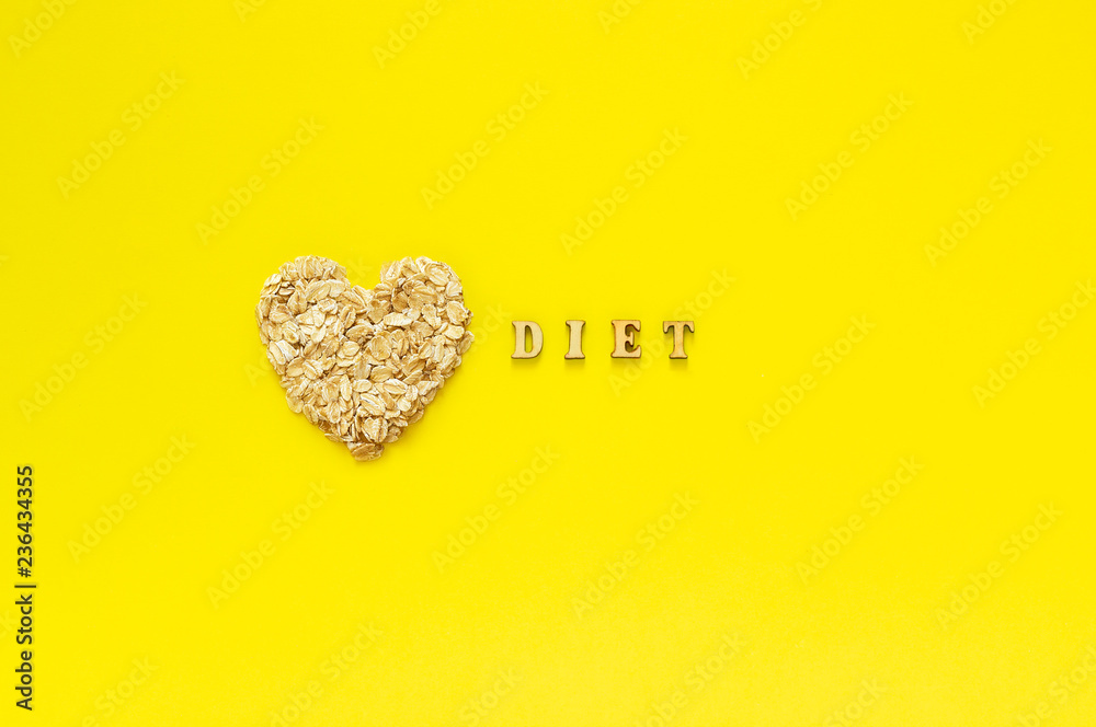 Text Diet and oatmeal oat flakes in shape heart on yellow background. Helthy organic diet concept. Top view Copy space Text Diet and oatmeal oat flakes in shape heart on yellow background. Helthy organic diet concept. Top view Copy space