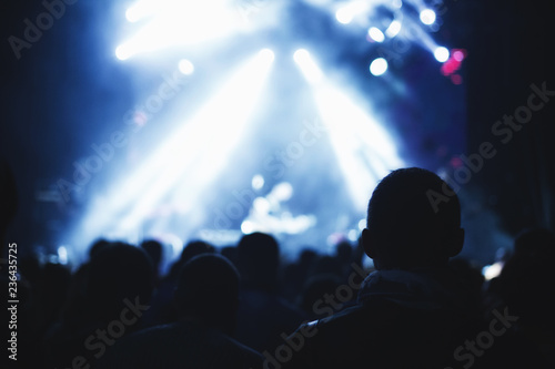 Silhouettes of a concert crowd in front of an illuminated stage in a nightclub. © Roman Rvachov