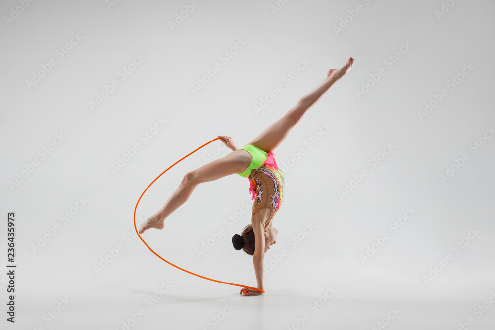 The teen female little girl doing gymnastics exercises with jump rope  isolated on a gray studio background. The gymnastic, stretch, fitness,  lifestyle, training, sport concept Stock Photo