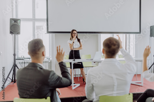 Colleagues asking a question to a businesswoman during a presentation. Business conference or training.