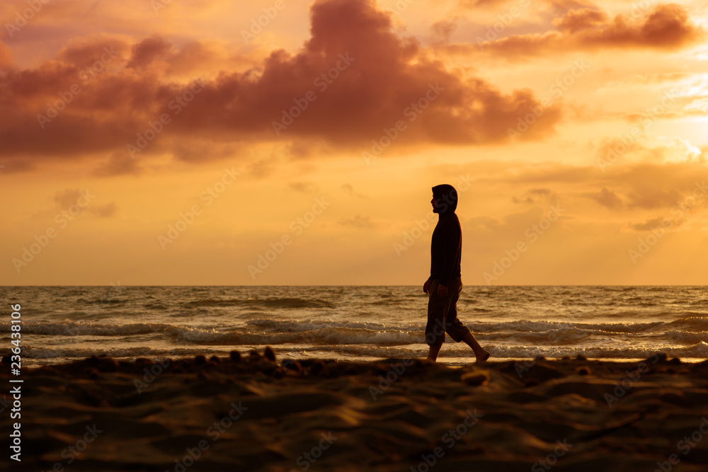 Man walks and thinks at sunset on the beach