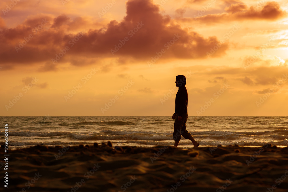 Man walks and thinks at sunset on the beach Man walks and thinks at sunset on the beach
