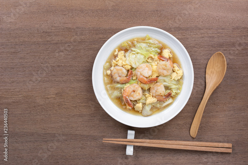 top view of stir fried cabbage with shrimp in a ceramic dish on wooden table. asian hommade style food concept. photo