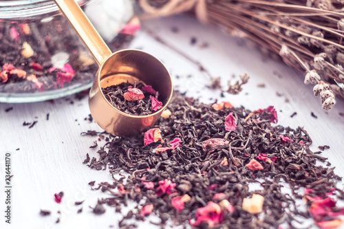 Heap of dry black tea with vanilla, cranberries, rose petals, pineapple on a wooden surface. Measuring Spoon For Tea.