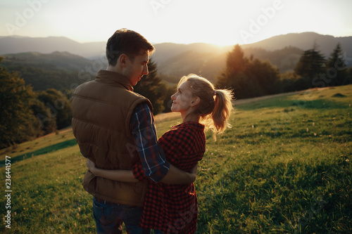 Young pretty couple hugging and smiling at the lake at sunset