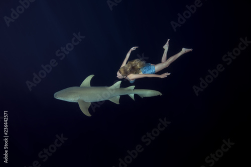 Young beautiful woman swim with shark in the night. Woman dives to Tawny nurse sharks (Nebrius ferrugineus) in Indian Ocean photo