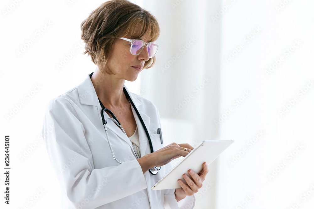 Confident female doctor using her digital tablet in the medical office. Confident female doctor using her digital tablet in the medical office.