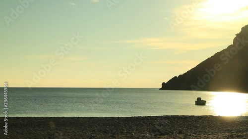 Scenic sunrise sun rising over sea surface and boat on water, Greece Peloponnese Lakonia, Vlychada Beach, Richea. Time lapse photo