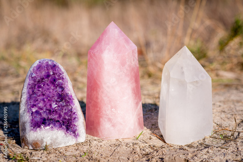 Golden Triangle gemstones: amethyst, rose quartz and white quartz, standing together in the grass