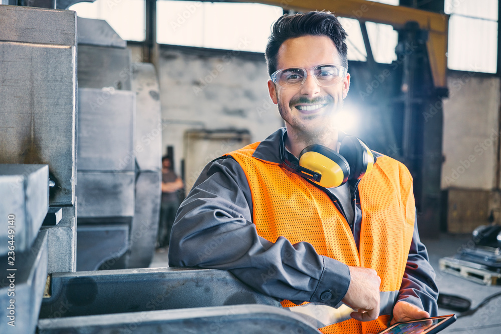 Portrait of smiling man wearing protective workwear and holding tablet in factory Portrait of smiling man wearing protective workwear and holding tablet in factory