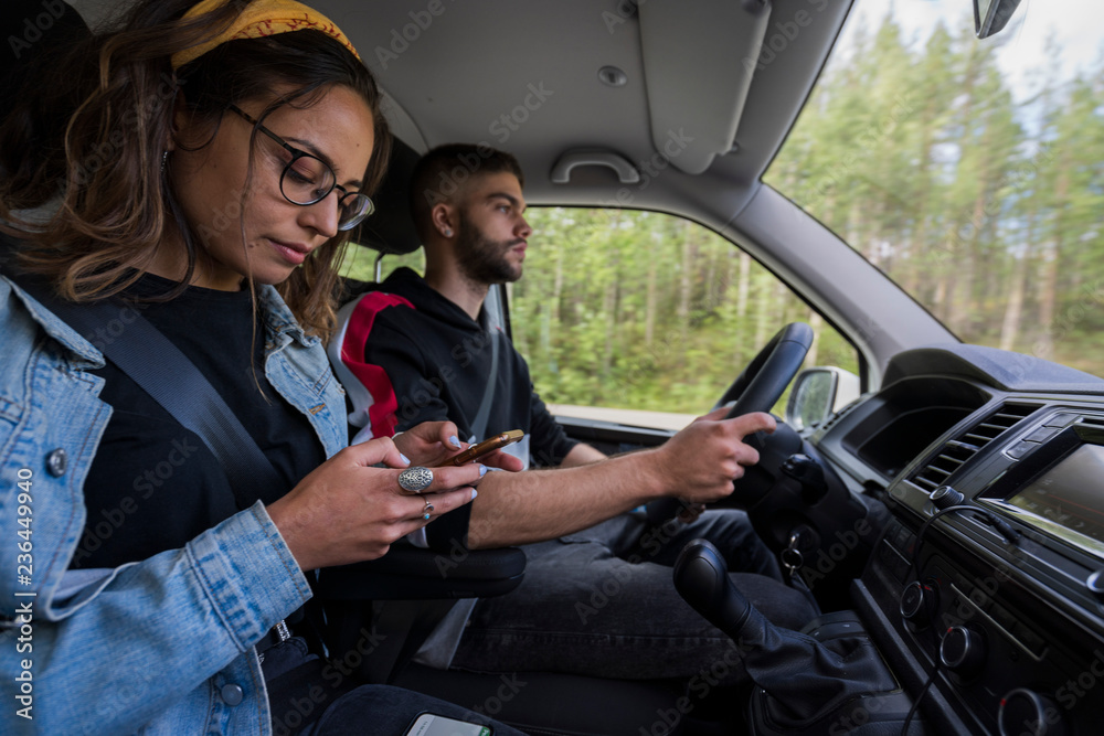 Young man driving car with woman checking cell phone Young man driving car with woman checking cell phone