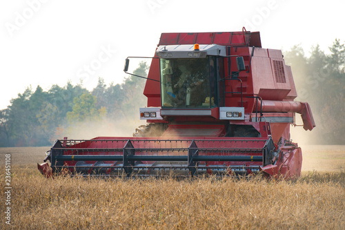 A combine creates a swirling haze of dust soybean chaff behind i