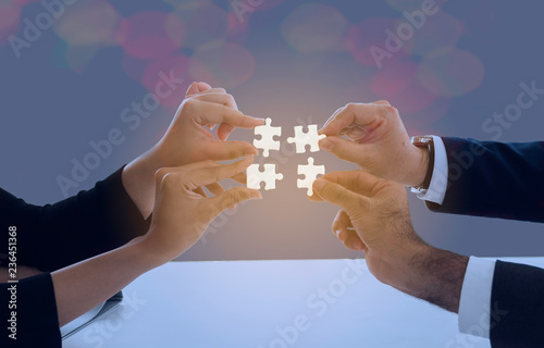 Image of businesswoman connecting elements of white puzzle photo