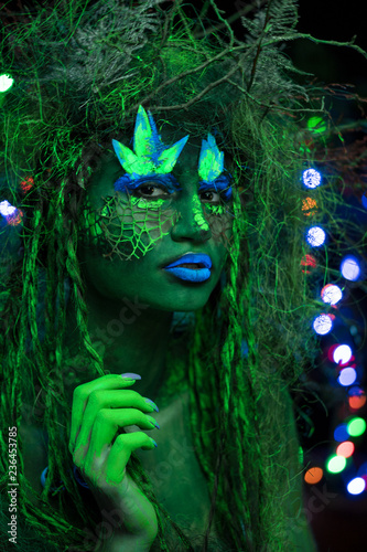 Mystic green dryad in UV fluor black light with Glowing trees on background