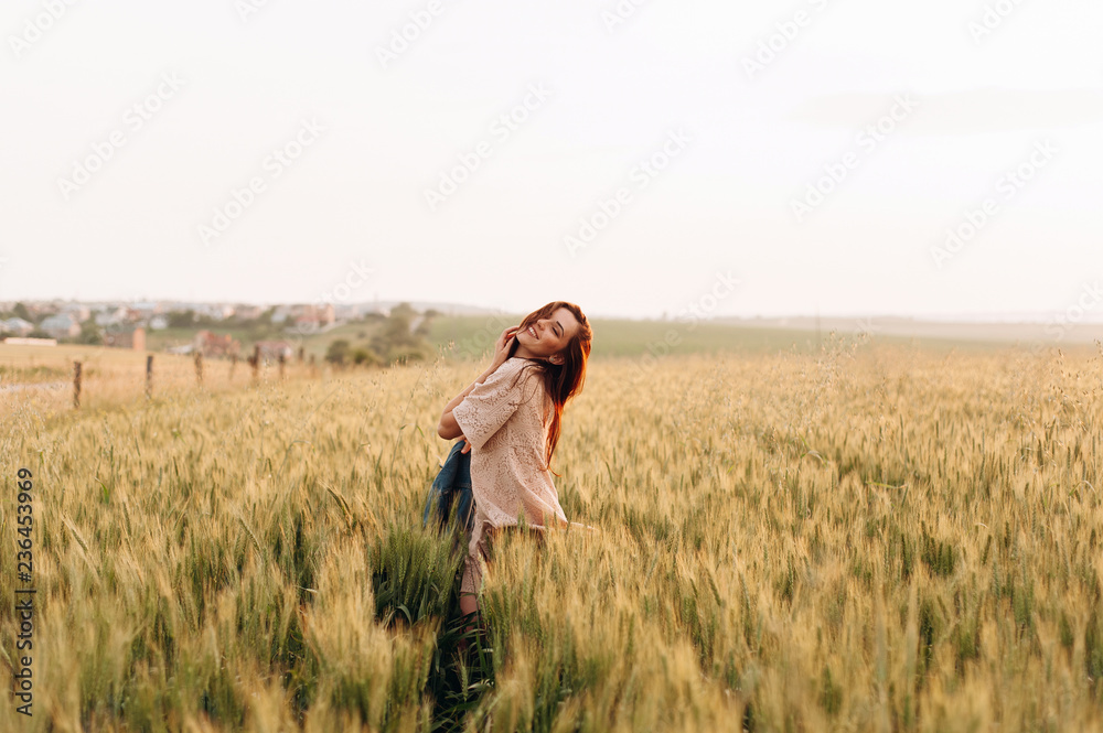 The beautiful girl in the dress is having fun on the field at sunset. Female psychology. The concept of freedom