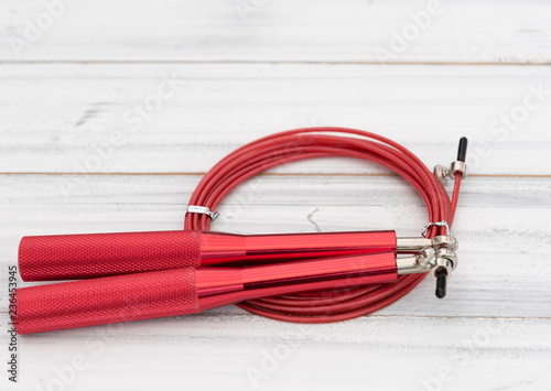 Modern red jump rope on white wooden background,flat lay photo