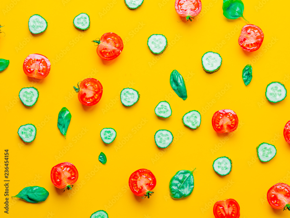 Above view at cutted tomatoes, cucumbers and basil on yellow background Above view at cutted tomatoes, cucumbers and basil on yellow background
