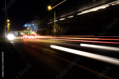 night road along the edges of the road there are lighting poles in the foreground traces of passing cars © metelevan