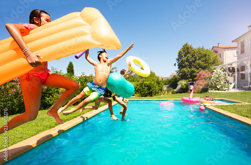 Funny teens with swim tools jumping into the pool