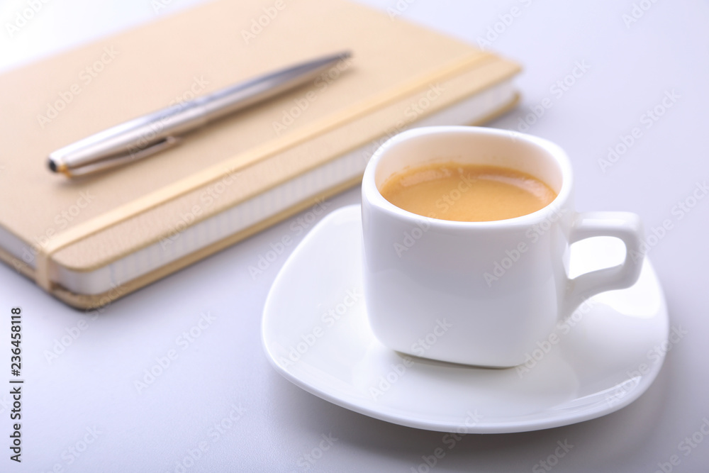 stylish notebook, ballpoint pen and white cup with a fragrant espresso coffee on the office desk. stylish notebook, ballpoint pen and white cup with a fragrant espresso coffee on the office desk.