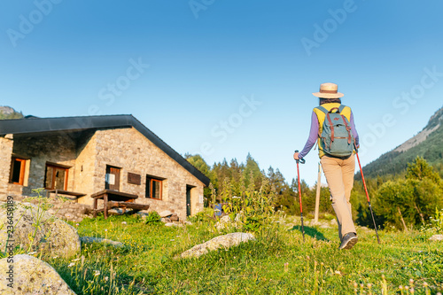 Young woman hiker camping near the beautiful shelter stone hut building in Pyrenees mountains. Hiking and adventure concept