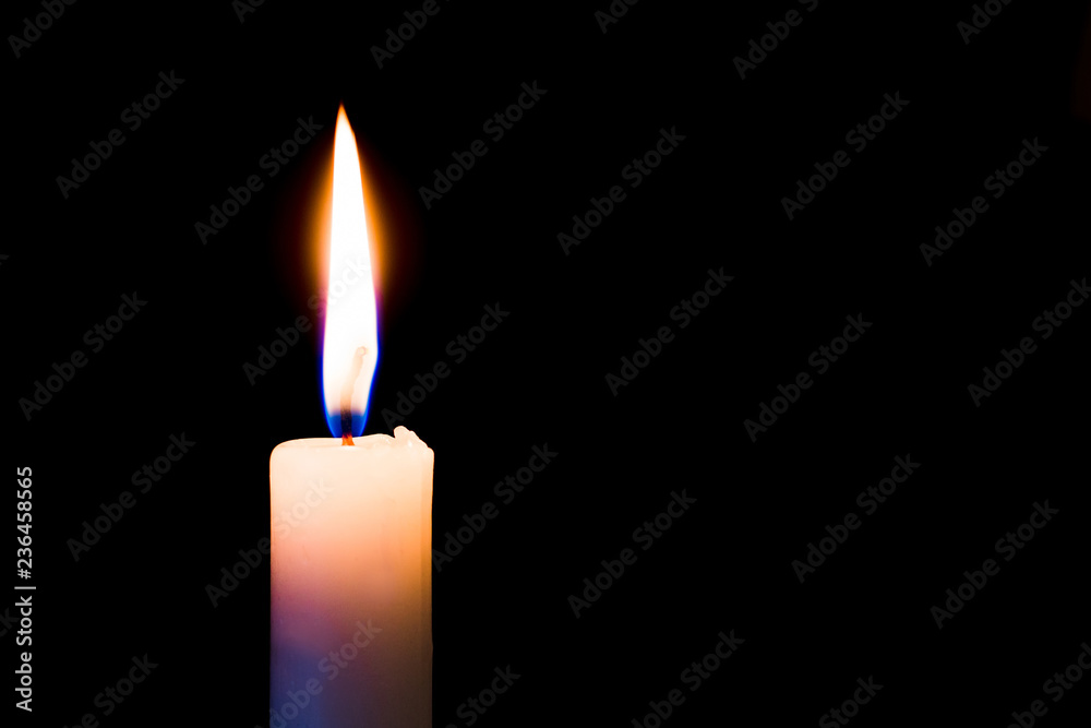 A candle burns brightly on a black, isolated background. Free space for text_ A candle burns brightly on a black, isolated background. Free space for text_