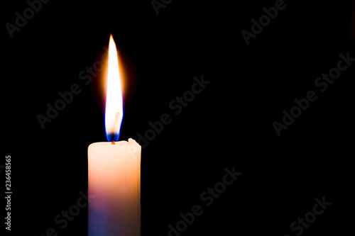 A candle burns brightly on a black, isolated background. Free space for text_