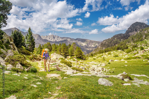 Young woman hiking in the mountains with a backpack and trekking poles. Mountain trail route concept © EdNurg