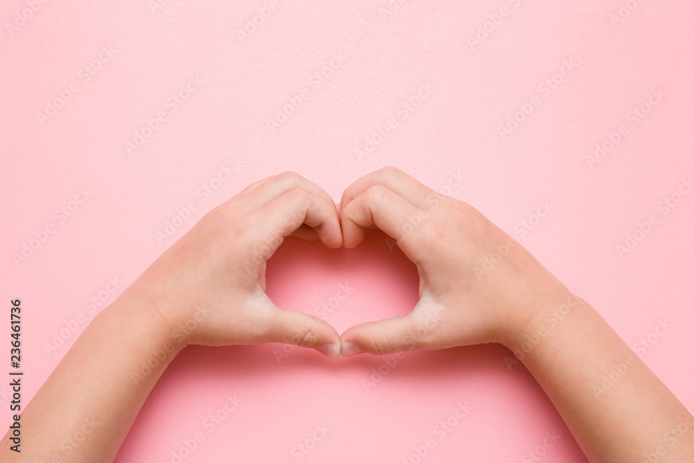 Heart shape created from little girl's hands on pastel pink background. Love, happiness and safety concept. Empty place for emotional, sentimental text, quote or sayings. Closeup. Point of view shot.
