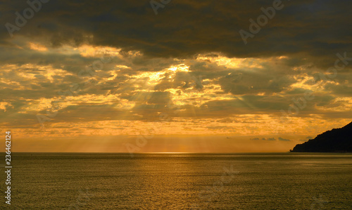 beautiful golden sunset over sea with clouds, mountain in backlight