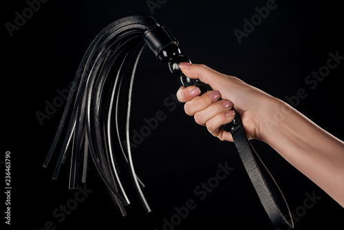 partial view of female hand holding leather flogging whip isolated on black