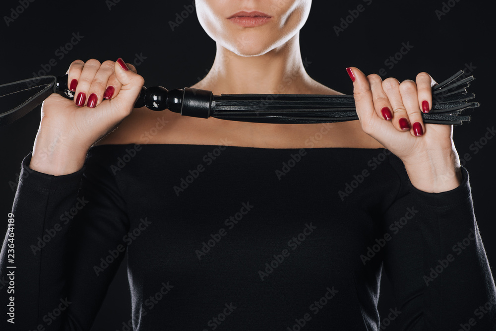 partial view of strict woman holding leather flogging whip isolated on  black Stock Photo