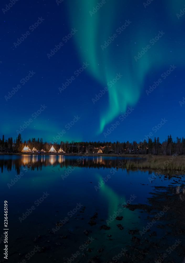 Magnificent grenish Northern light with refection in a lake at Yellow knife, Canada