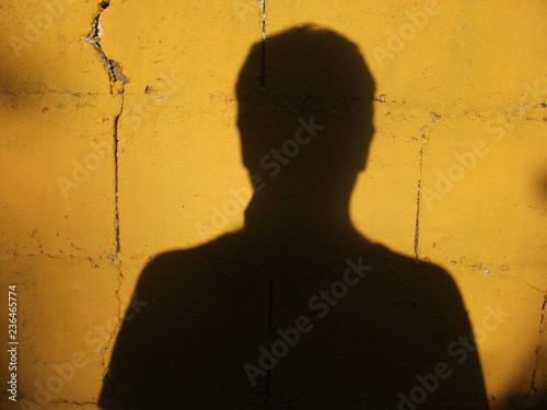 PRESENCIA - Sombra de una persona sobre una pared amarilla photo