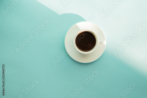 Cup of steaming coffee on seafoam green table, top view. Abstract photo of hot espresso drink on pale blue-green background.
