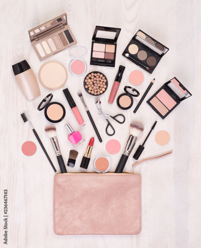 Makeup cosmetics and accessories and an open bag on white wooden background, top view Makeup cosmetics and accessories and an open bag on white wooden background, top view