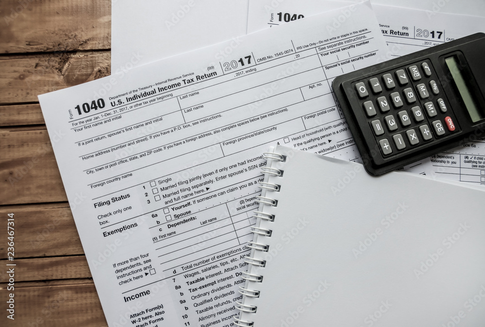 1040 tax form, calculator and notepad on the table 1040 tax form, calculator and notepad on the table