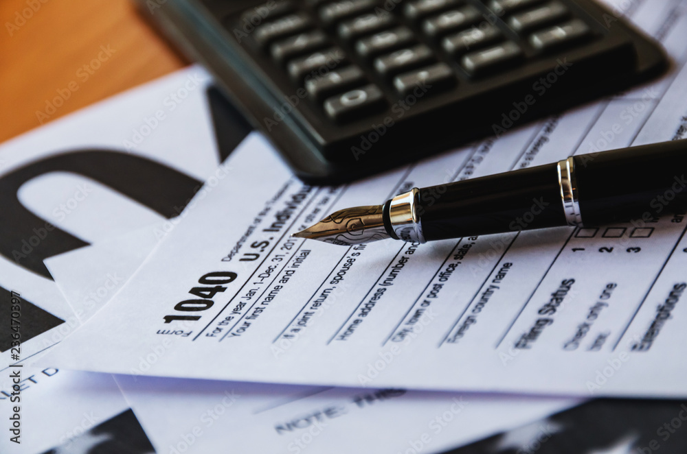 1040 tax form, pen and calculator on the table 1040 tax form, pen and calculator on the table
