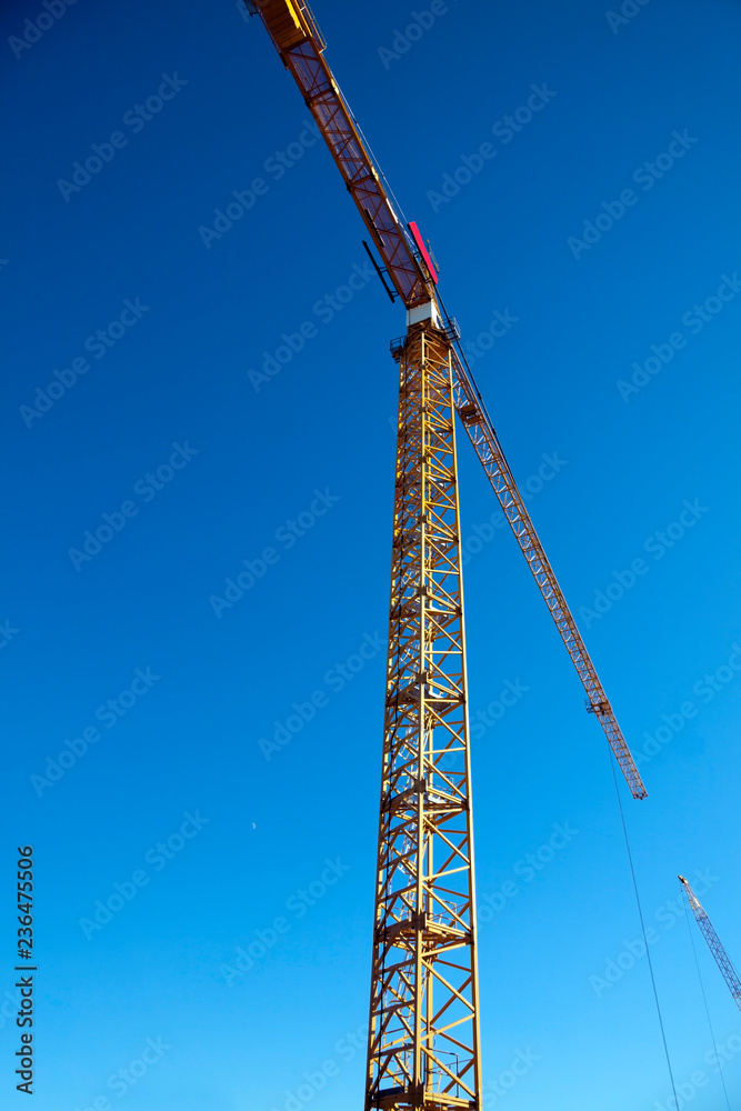 Tower crane against blue sky. Vertical. Tower crane against blue sky. Vertical.