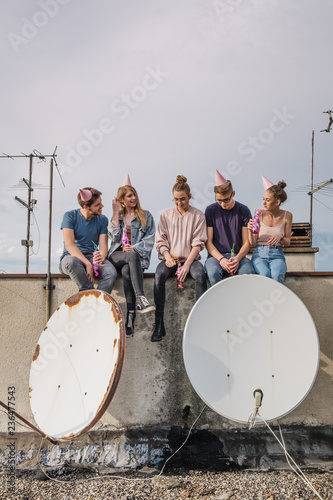 Group of teenage friends drinking beer and coctails on the roof at party  photo