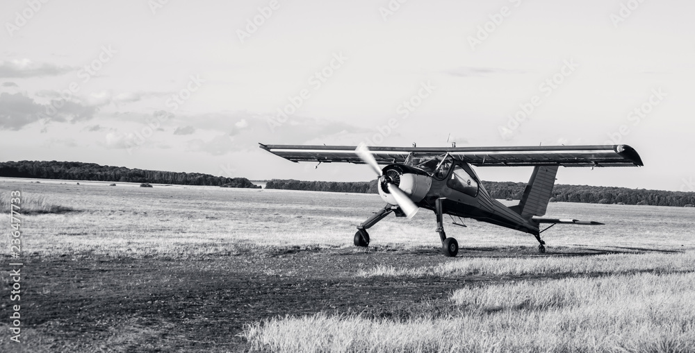 Fototapeta premium Training and sports light aircraft in the field landing takeoff. Black and white photo of a training aircraft