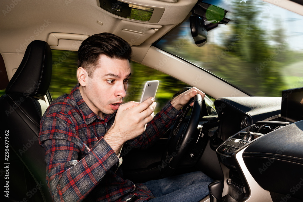 Man sitting inside car with mobile phone in hand texting while driving